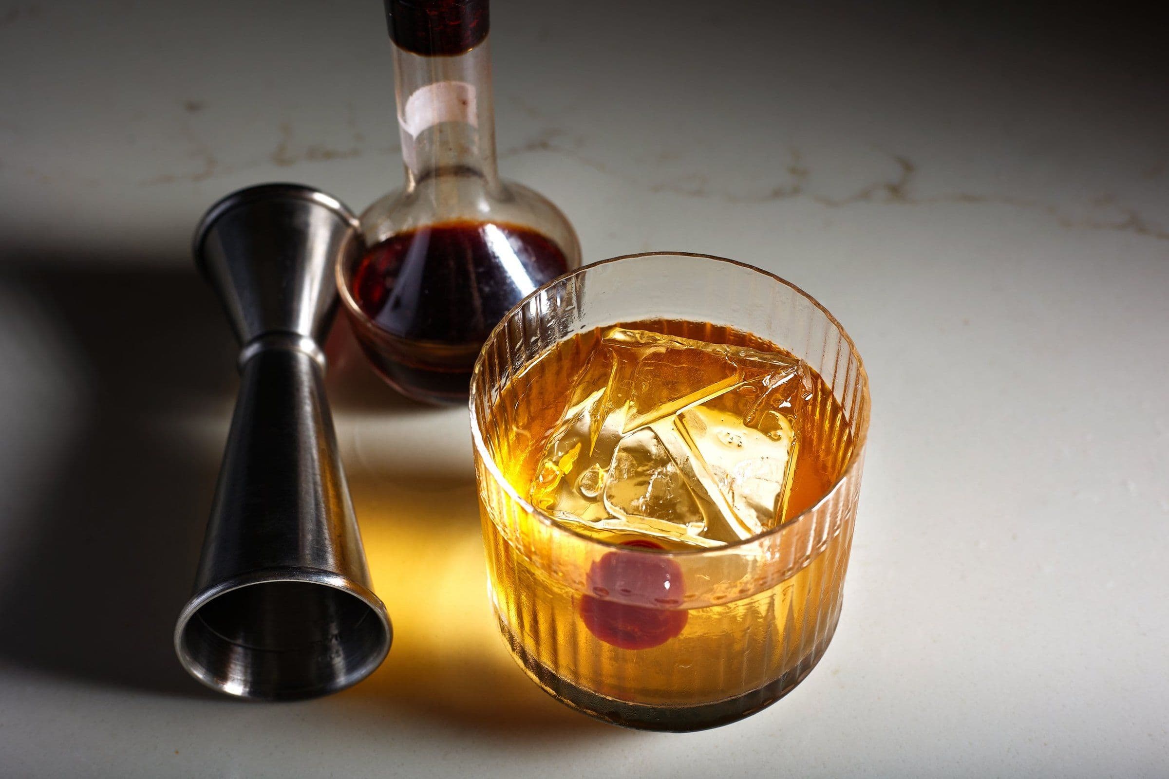 Old fashioned with a clear ice cube and a jigger
