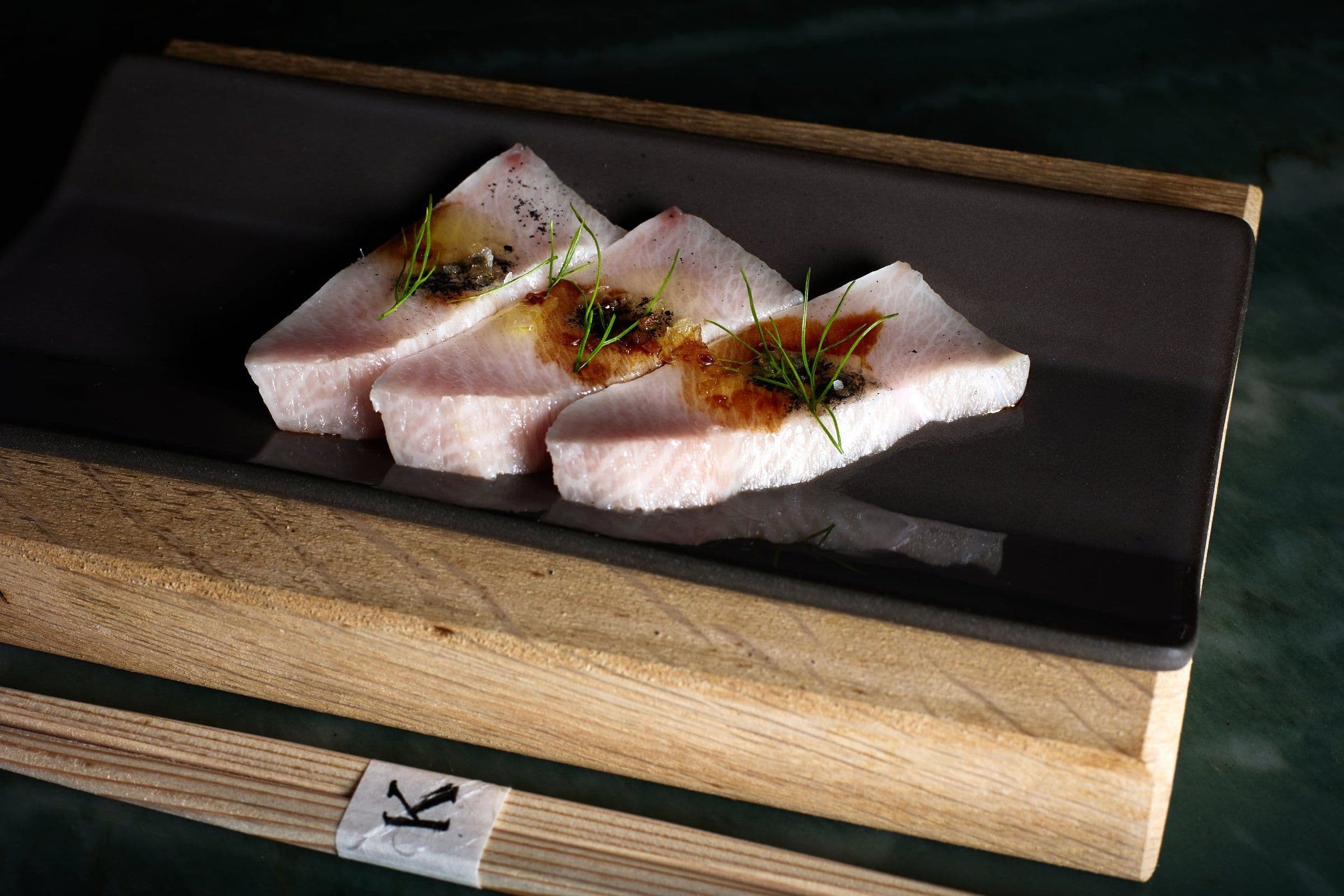 Seared yellowtail slices on a cedar board